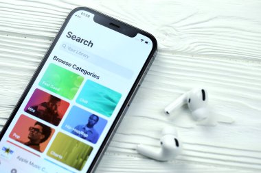 KHARKOV, UKRAINE - 5 Mart 2021: Apple müzik simgesi ve uygulaması iPhone 12 profosyonel ekranda beyaz ahşap masadaki uçak podları profosyoneli