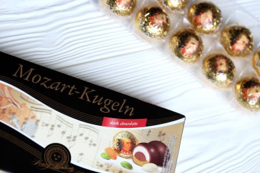 KHARKOV, UKRAINE - 19 Nisan 2021: Henry Lambertz Mozart-Kugeln lüks siyah çikolata şekerlemeleri beyaz ahşap masa üzerindeki kara kutuda