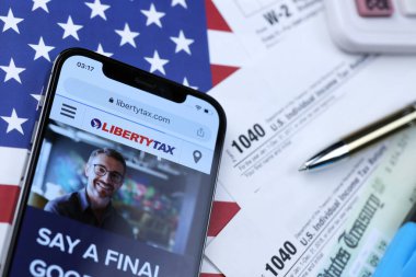 KHARKOV, UKRAINE - 5 Mart 2021: ABD bayrağında 1040 ve w-2 kağıt vergi formlarıyla birlikte iPhone 12 profesyonel ekranda LibertyVerx web sitesi