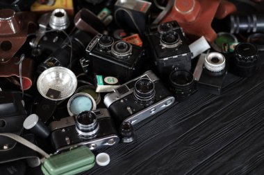 KHARKOV, UKRAINE - 27 Nisan 2021: Fotoğraf makineleri ve fotoğrafçı karanlık odasındaki siyah ahşap masada eski bir fotoğraf makinesi. Sovyetler Birliği zamanından fotoğraf malzemeleri.