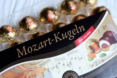 KHARKOV, UKRAINE - 19 Nisan 2021: Henry Lambertz Mozart-Kugeln lüks siyah çikolata şekerlemeleri beyaz ahşap masa üzerindeki kara kutuda