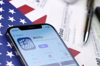 KHARKOV, UKRAINE - 5 Mart 2021: IRS2GO uygulaması iPhone 12 profesyonel ekranda 1040 ve W-2 ABD bayrağında kağıt vergi formları