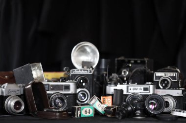 KHARKOV, UKRAINE - 27 Nisan 2021: Fotoğraf makineleri ve fotoğrafçı karanlık odasındaki siyah ahşap masada eski bir fotoğraf makinesi. Sovyetler Birliği zamanından fotoğraf malzemeleri.