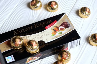KHARKOV, UKRAINE - 19 Nisan 2021: Henry Lambertz Mozart-Kugeln lüks siyah çikolata şekerlemeleri beyaz ahşap masa üzerindeki kara kutuda