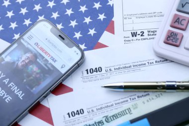 KHARKOV, UKRAINE - 5 Mart 2021: ABD bayrağında 1040 ve w-2 kağıt vergi formlarıyla birlikte iPhone 12 profesyonel ekranda LibertyVerx web sitesi