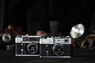 KHARKOV, UKRAINE - 27 Nisan 2021: Fed 4 ve 5b Film fotoğraf makinesi ve fotoğrafçı karanlık odasındaki siyah ahşap masada eski bir fotoğraf makinesi. Sovyetler Birliği zamanından fotoğraf malzemeleri.