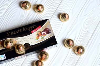 KHARKOV, UKRAINE - 19 Nisan 2021: Henry Lambertz Mozart-Kugeln lüks siyah çikolata şekerlemeleri beyaz ahşap masa üzerindeki kara kutuda