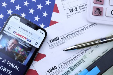 KHARKOV, UKRAINE - 5 Mart 2021: ABD bayrağında 1040 ve w-2 kağıt vergi formlarıyla birlikte iPhone 12 profesyonel ekranda LibertyVerx web sitesi