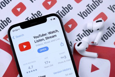 KHARKOV, UKRAINE - 5 Mart 2021: Youtube simgesi ve uygulaması iPhone 12 profosyonel ekranda beyaz ahşap masadaki uçak podları profosyoneli