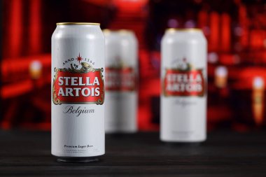 KHARKOV, UKRAINE - 14 Şubat 2021: Stella Artois bira kutuları ahşap masa üzerinde arka planda kırmızı çubuk ile. Alkol üretimi