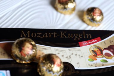 KHARKOV, UKRAINE - 19 Nisan 2021: Henry Lambertz Mozart-Kugeln lüks siyah çikolata şekerlemeleri beyaz ahşap masa üzerindeki kara kutuda