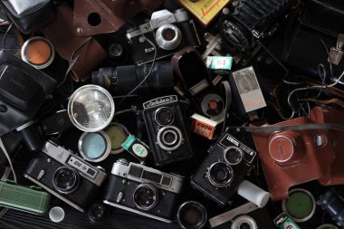 KHARKOV, UKRAINE - 27 Nisan 2021: Fotoğraf makineleri ve fotoğrafçı karanlık odasındaki siyah ahşap masada eski bir fotoğraf makinesi. Sovyetler Birliği zamanından fotoğraf malzemeleri.
