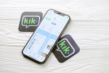 KHARKOV, UKRAINE - 5 Mart 2021: Kik simgesi ve uygulaması iPhone 12 'den beyaz ahşap masadaki profesyonel ekranda