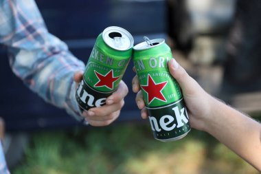 KHARKOV, UKRAINE - 31 Temmuz 2021: Erkeklerin ellerinde yeşil teneke kutu Heineken soluk bira