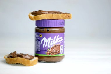 KHARKOV, UKRAINE - 2 Temmuz 2021: Beyaz ahşap masa üzerinde klasik leylak rengi tasarımı ile yayılmış Milka tatlandırılmış fındık kakaosu kutusu