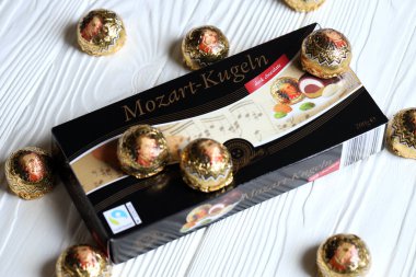 KHARKOV, UKRAINE - 19 Nisan 2021: Henry Lambertz Mozart-Kugeln lüks siyah çikolata şekerlemeleri beyaz ahşap masa üzerindeki kara kutuda