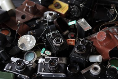 KHARKOV, UKRAINE - 27 Nisan 2021: Fotoğraf makineleri ve fotoğrafçı karanlık odasındaki siyah ahşap masada eski bir fotoğraf makinesi. Sovyetler Birliği zamanından fotoğraf malzemeleri.