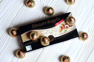 KHARKOV, UKRAINE - 19 Nisan 2021: Henry Lambertz Mozart-Kugeln lüks siyah çikolata şekerlemeleri beyaz ahşap masa üzerindeki kara kutuda