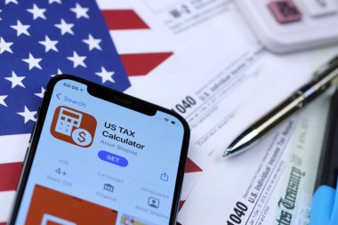 KHARKOV, UKRAINE - 5 Mart 2021: ABD Vergi Hesap Makinesi uygulaması iPhone 12 profesyonel ekranda 1040 ve W-2 kağıt vergi formları ABD bayrağında