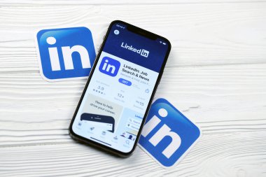KHARKOV, UKRAINE - 5 Mart 2021: Beyaz ahşap masadaki iPhone 12 profesyonel ekranda Uygulama mağazasından gelen Linkedin simgesi ve uygulaması