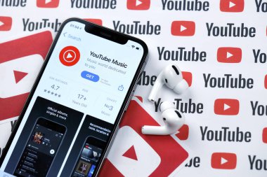 KHARKOV, UKRAINE - 5 Mart 2021: Youtube müzik simgesi ve uygulaması iPhone 12 profesyonel ekranda beyaz ahşap masadaki uçak podları profosyoneli