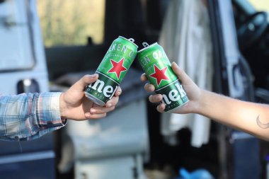 KHARKOV, UKRAINE - 31 Temmuz 2021: Erkeklerin ellerinde yeşil teneke kutu Heineken soluk bira