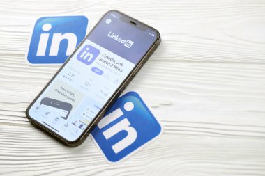 KHARKOV, UKRAINE - 5 Mart 2021: Beyaz ahşap masadaki iPhone 12 profesyonel ekranda Uygulama mağazasından gelen Linkedin simgesi ve uygulaması