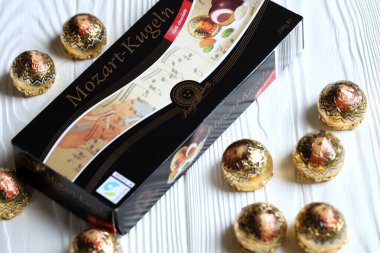 KHARKOV, UKRAINE - 19 Nisan 2021: Henry Lambertz Mozart-Kugeln lüks siyah çikolata şekerlemeleri beyaz ahşap masa üzerindeki kara kutuda