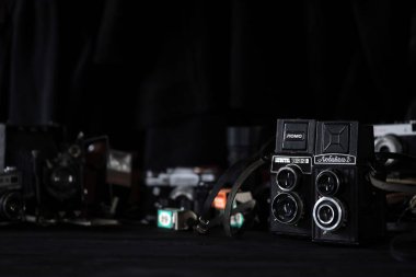 KHARKOV, UKRAINE - 27 Nisan 2021: Lubitel 166b ve 2 Film kamerası ve fotoğrafçı karanlık odasındaki siyah ahşap masada eski bir fotoğraf makinesi. Sovyetler Birliği zamanından fotoğraf malzemeleri.