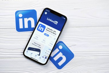 KHARKOV, UKRAINE - 5 Mart 2021: Beyaz ahşap masadaki iPhone 12 profesyonel ekranda Uygulama mağazasından gelen Linkedin simgesi ve uygulaması