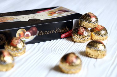 KHARKOV, UKRAINE - 19 Nisan 2021: Henry Lambertz Mozart-Kugeln lüks siyah çikolata şekerlemeleri beyaz ahşap masa üzerindeki kara kutuda