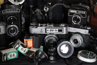 KHARKOV, UKRAINE - 27 Nisan 2021: Fotoğraf makineleri ve fotoğrafçı karanlık odasındaki siyah ahşap masada eski bir fotoğraf makinesi. Sovyetler Birliği zamanından fotoğraf malzemeleri.