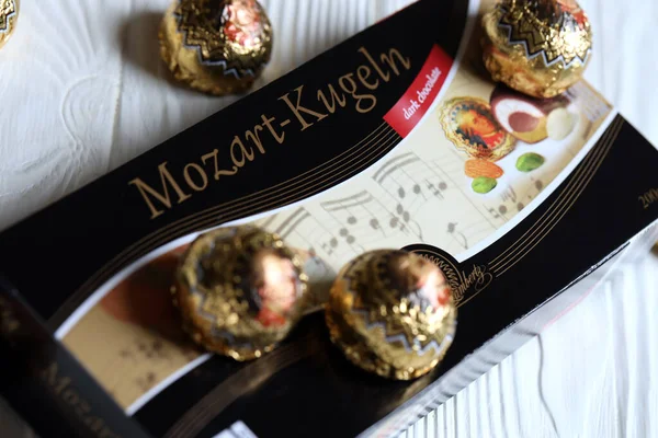 KHARKOV, UKRAINE - 19 Nisan 2021: Henry Lambertz Mozart-Kugeln lüks siyah çikolata şekerlemeleri beyaz ahşap masa üzerindeki kara kutuda