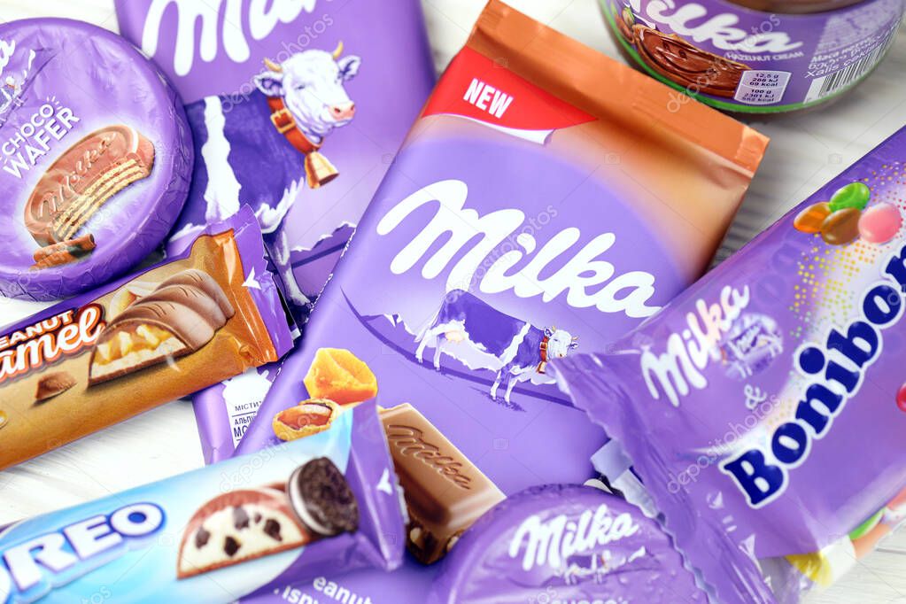 KHARKOV, UKRAINE - JULY 2, 2021: Milka chocolate products with classical lilac color wrapping design on white wooden table