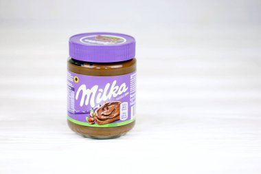 KHARKOV, UKRAINE - 2 Temmuz 2021: Beyaz ahşap masa üzerinde klasik leylak rengi tasarımı ile yayılmış Milka tatlandırılmış fındık kakaosu kutusu