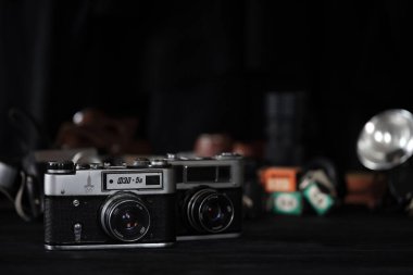 KHARKOV, UKRAINE - 27 Nisan 2021: Fed 4 ve 5b Film fotoğraf makinesi ve fotoğrafçı karanlık odasındaki siyah ahşap masada eski bir fotoğraf makinesi. Sovyetler Birliği zamanından fotoğraf malzemeleri.