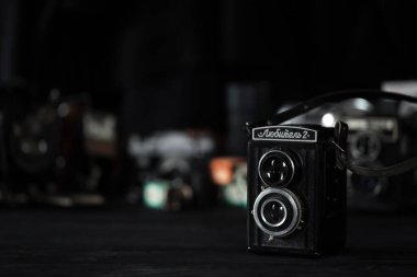 KHARKOV, UKRAINE - 27 Nisan 2021: Lubitel 166b ve 2 Film kamerası ve fotoğrafçı karanlık odasındaki siyah ahşap masada eski bir fotoğraf makinesi. Sovyetler Birliği zamanından fotoğraf malzemeleri.