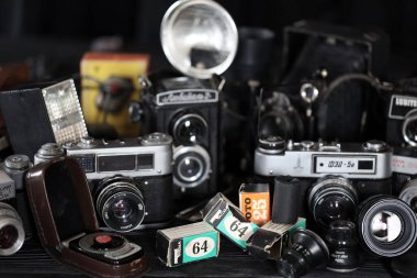 KHARKOV, UKRAINE - 27 Nisan 2021: Fotoğraf makineleri ve fotoğrafçı karanlık odasındaki siyah ahşap masada eski bir fotoğraf makinesi. Sovyetler Birliği zamanından fotoğraf malzemeleri.