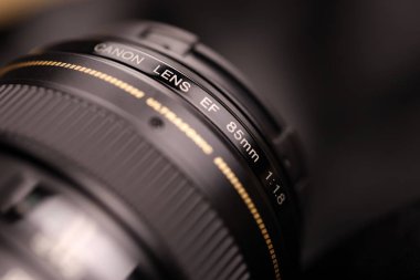 KHARKOV, UKRAINE - 21 Ocak 2021: Siyah kumaş zemin üzerinde Canon EF 85mm 1.8 lens. Canon marka ürününün ayrıntılı fotoğrafı