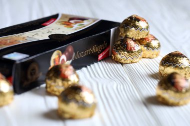 KHARKOV, UKRAINE - 19 Nisan 2021: Henry Lambertz Mozart-Kugeln lüks siyah çikolata şekerlemeleri beyaz ahşap masa üzerindeki kara kutuda