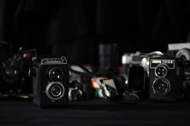 KHARKOV, UKRAINE - 27 Nisan 2021: Lubitel 166b ve 2 Film kamerası ve fotoğrafçı karanlık odasındaki siyah ahşap masada eski bir fotoğraf makinesi. Sovyetler Birliği zamanından fotoğraf malzemeleri.