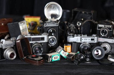 KHARKOV, UKRAINE - 27 Nisan 2021: Fotoğraf makineleri ve fotoğrafçı karanlık odasındaki siyah ahşap masada eski bir fotoğraf makinesi. Sovyetler Birliği zamanından fotoğraf malzemeleri.
