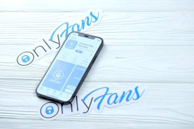 KHARKOV, UKRAINE - 5 Mart 2021: Onlyfan simgesi ve uygulaması iPhone 12 'den beyaz ahşap masadaki profesyonel ekranda