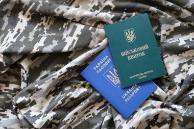 Ukrayna askeri kimliği ve piksel kamuflaj dokusuna sahip yabancı pasaport. Gri, kahverengi ve yeşil pikselli kamuflaj desenli kumaş Ukrayna ordusuna ait kişisel jeton ve pasaport..