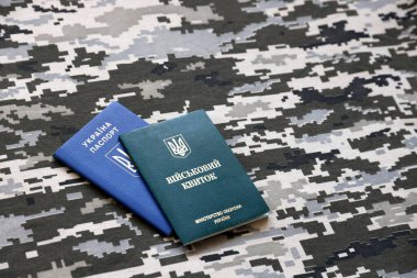 Ukrayna askeri kimliği ve piksel kamuflaj dokusuna sahip yabancı pasaport. Gri, kahverengi ve yeşil pikselli kamuflaj desenli kumaş Ukrayna ordusuna ait kişisel jeton ve pasaport..