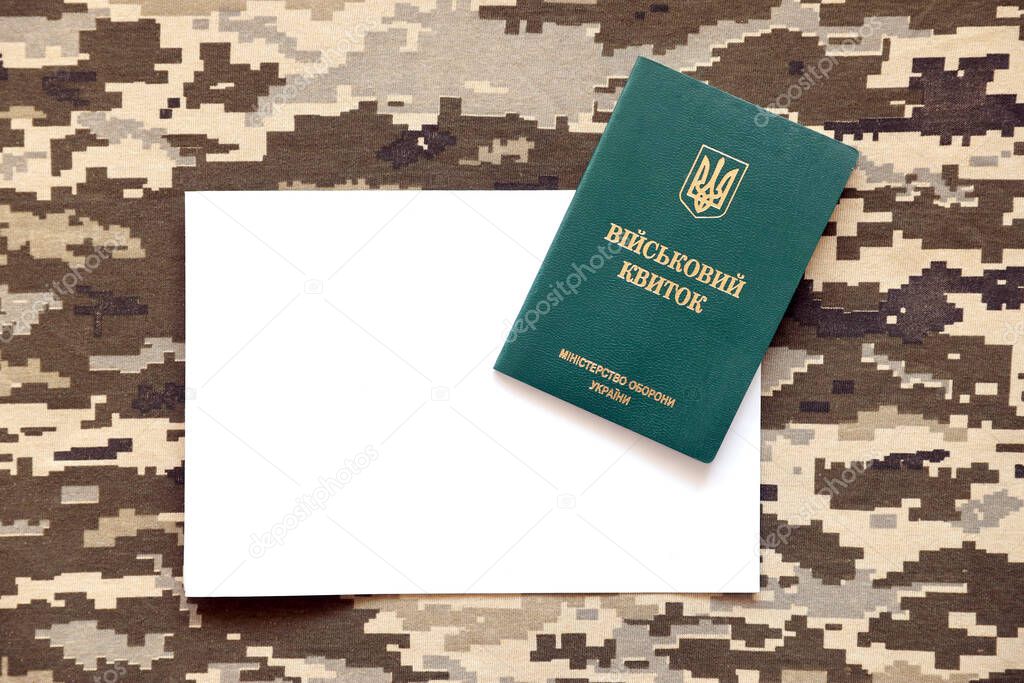 Ukrainian military ID and blank paper sheet on fabric with texture of pixeled camouflage. Cloth with camo pattern in grey, brown and green pixel shapes with Ukrainian army personal token close up.