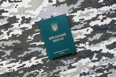 Piksel kamuflaj dokusuna sahip kumaş üzerinde Ukrayna askeri kimliği. Gri, kahverengi ve yeşil pikselli kamuflaj desenli kumaş Ukrayna ordusunun kişisel jetonuyla yakın plan..