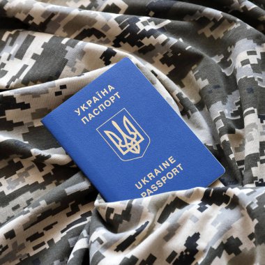 Askeri kamuflajlı kumaş dokusunda Ukrayna pasaportu. Gri, kahverengi ve yeşil pikselli kamuflaj desenli kumaş ve Ukrayna kimlik kartı.