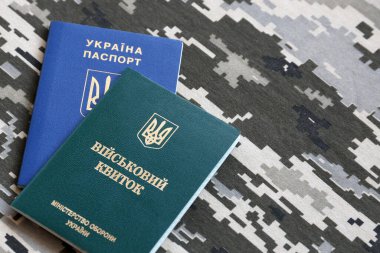 Ukrayna askeri kimliği ve piksel kamuflaj dokusuna sahip yabancı pasaport. Gri, kahverengi ve yeşil pikselli kamuflaj desenli kumaş Ukrayna ordusuna ait kişisel jeton ve pasaport..