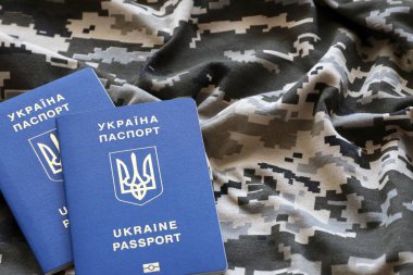 Askeri kamuflajlı kumaş dokusunda Ukrayna pasaportu. Gri, kahverengi ve yeşil pikselli kamuflaj desenli kumaş ve Ukrayna kimlik kartı.